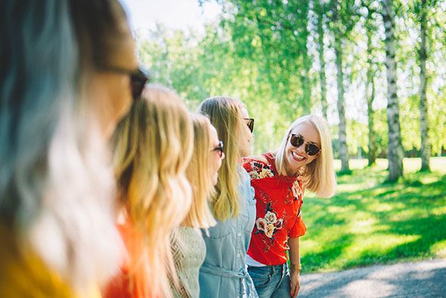 Naiset lenkkipolulla kampusrannalla metsikön edessä nauraen.