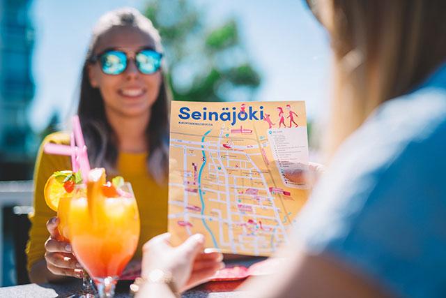 Naiset tutkailevat Seinäjoen keskustan karttaa drinkkien äärellä.