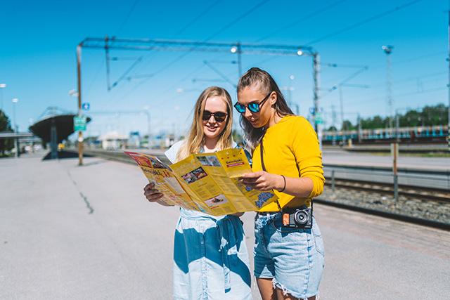 Naiset tutkailevat Seinäjoen keskustan karttaa juna-asemalla.