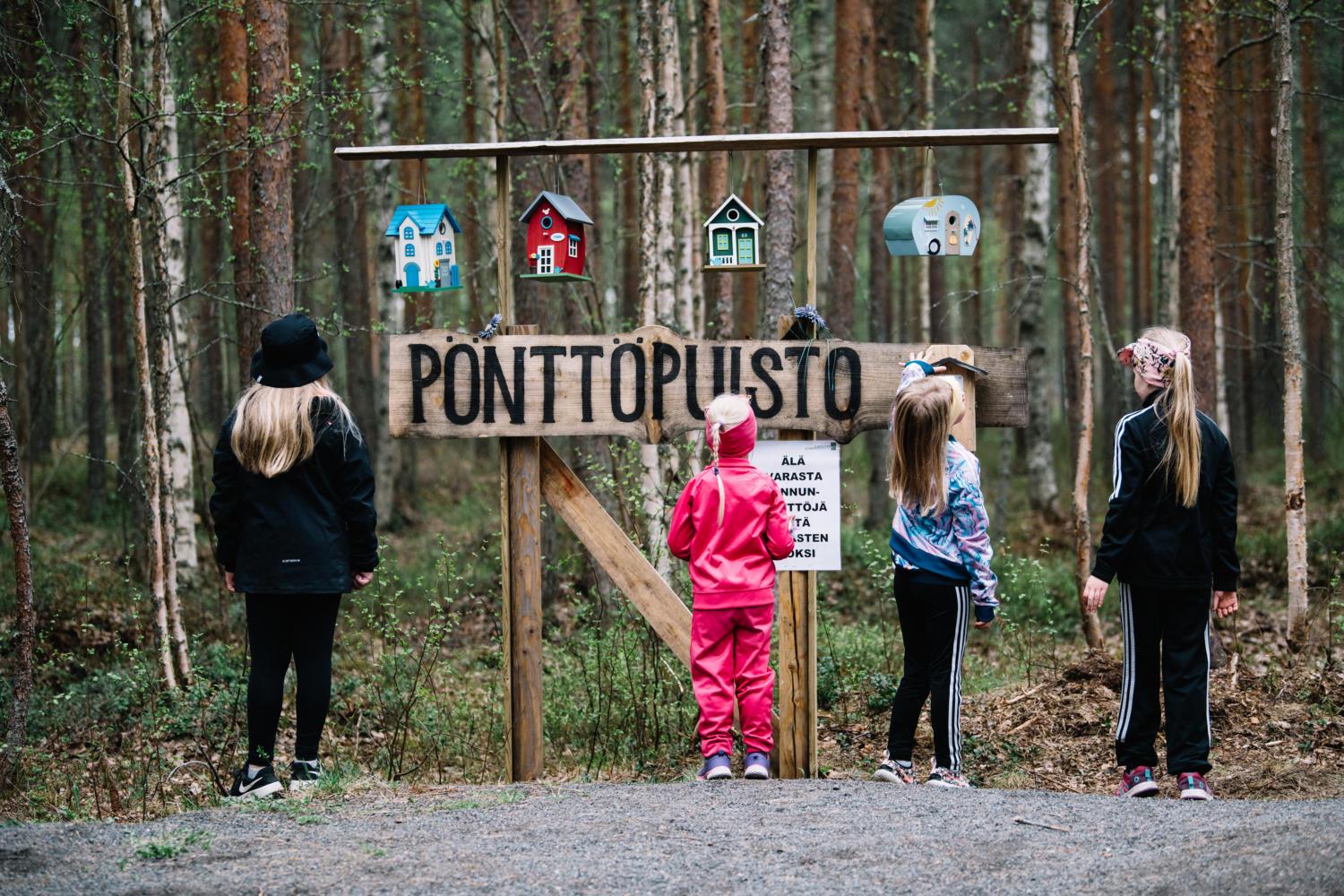 Lapset katselemassa lastenreitti Oravapolun Pönttöpuiston värikkäitä pönttöjä.