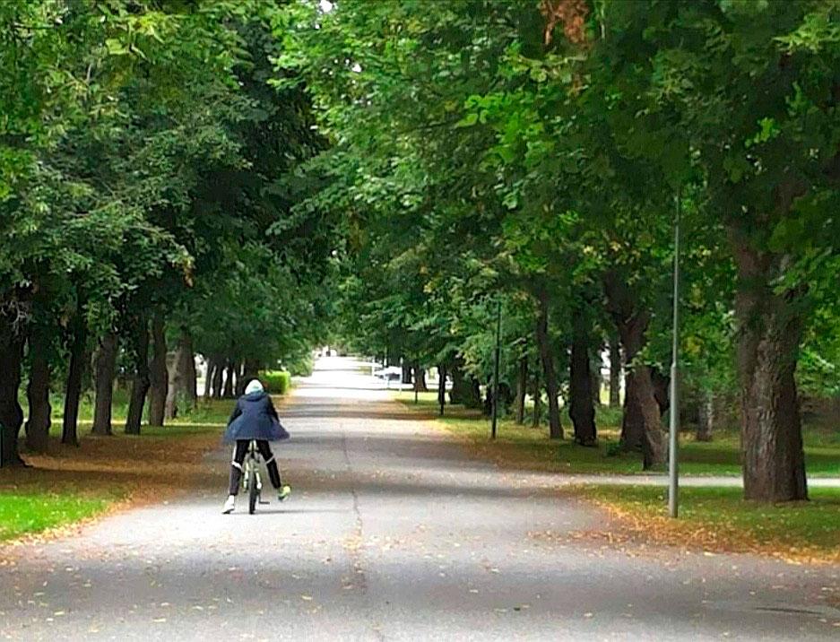 Pyöräilijä ajaa Piirin alueen vehreällä puistoalueella.