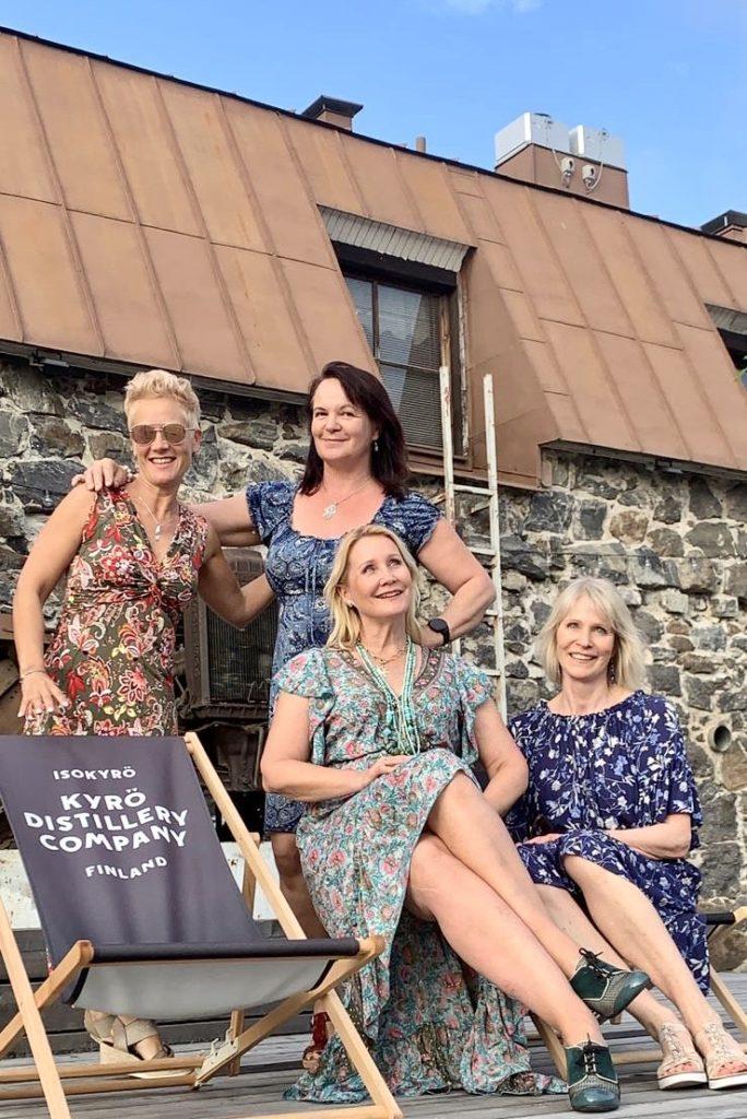 Naiset istuvat Kyrö Distilleryn terassilla uudet värikkäät mekot yllään