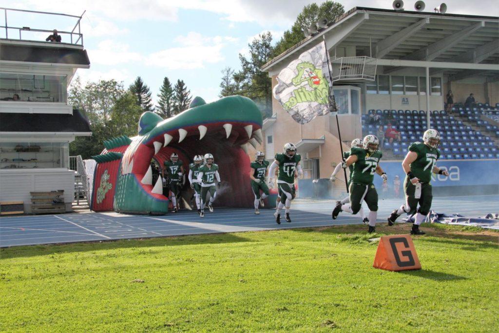 Amerikkalaisen jalkapallon joukkue Crocodiles saapuu kentälle Krokotiilin suusta.
