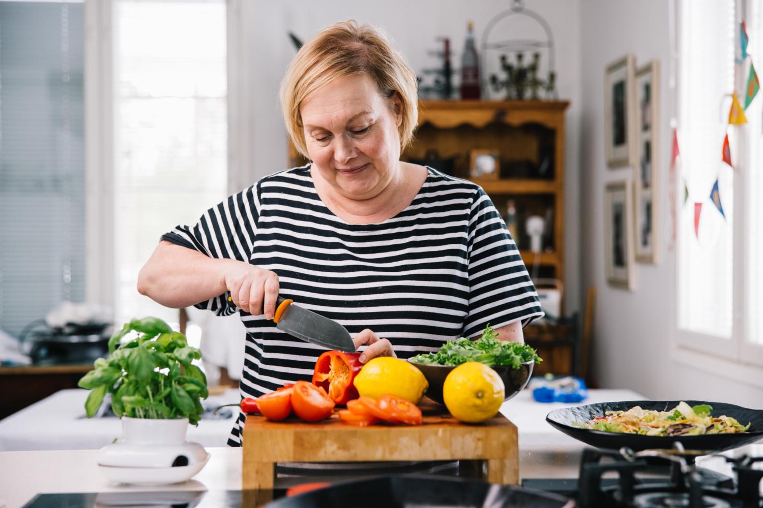 Nanna Rintala leikkaamassa tuoreita vihanneksia leikkuulaudalla