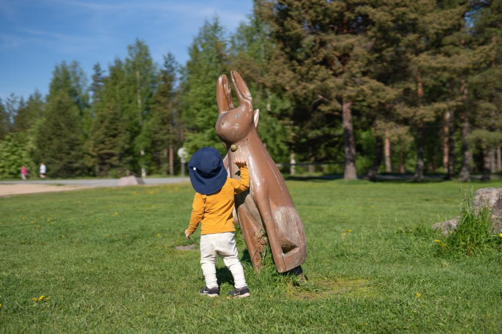 Lapsi silittää jäniksen muotoista patsasta.