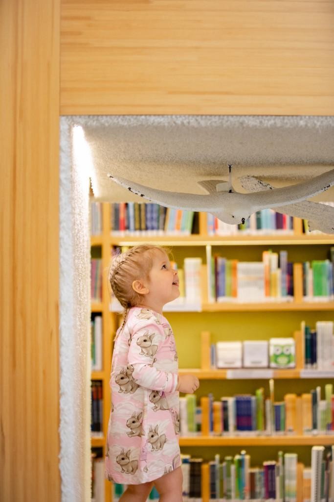 Lapsi hymyilee kirjaston lastenosaston oleskelukopissa.