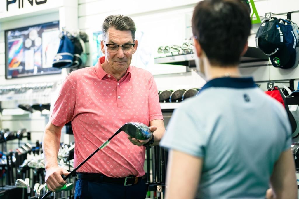 Golfaaja ostamassa uutta mailaa myyjän avustamana.
