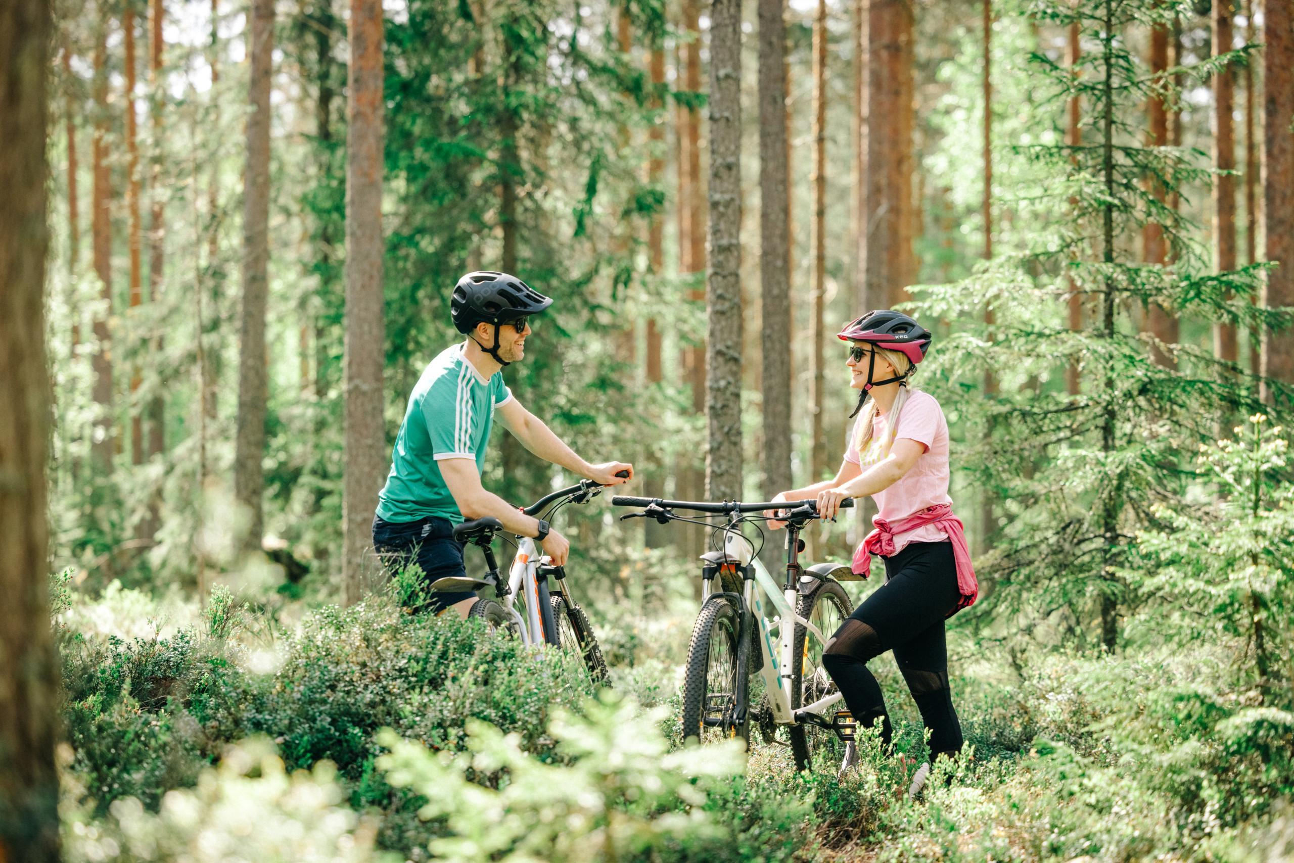 Pariskunta pyöräilee metsäisellä pyöräreitillä
