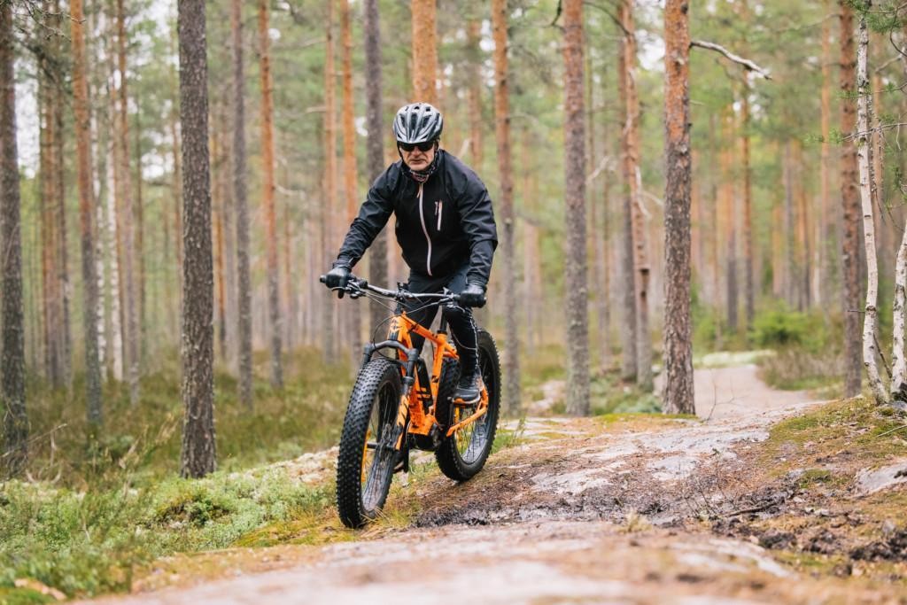 Maastopyöräilijä pyöräilee fatbikepyörällä metsäreitillä