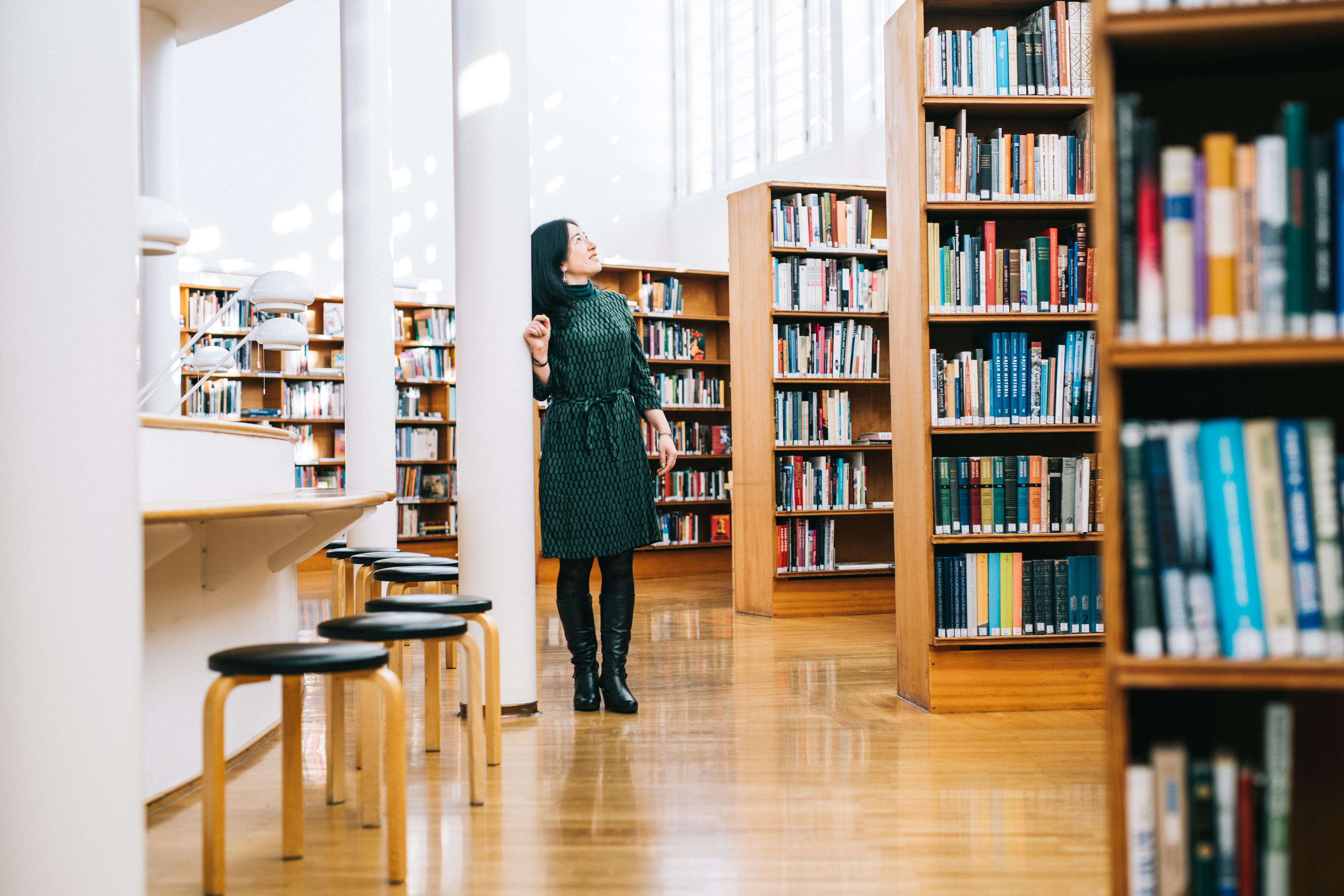 Kirjaston vieras nojaa Aalto-kirjaston pilariin ihaillen kirjaton arkkitehtuurisia elementtejä.