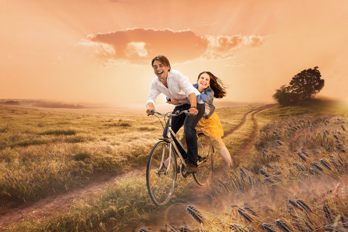 Niin kuin taivaassa pressikuva, jossa pariskunta pyöräilee peltotiellä auringonlaskussa