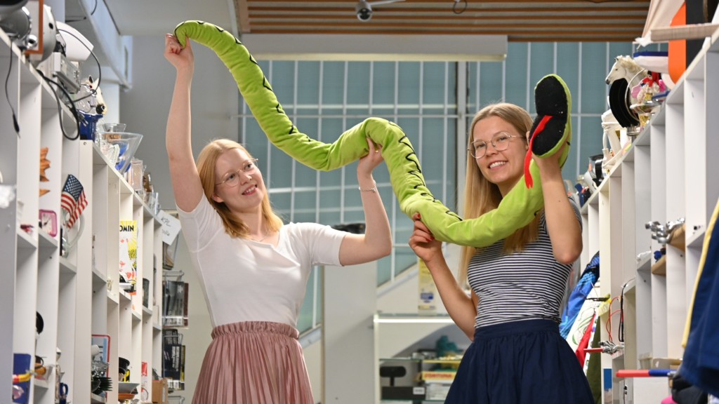 Kaksi naista pitelevät käsissään vihreää pehmolelukäärmettä