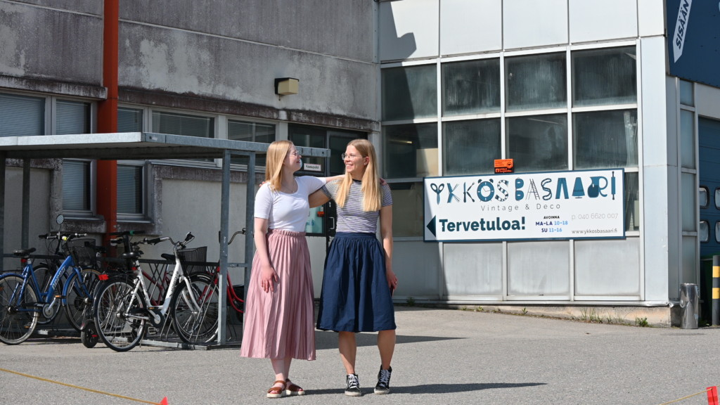 Kaksi nuorta naista Ykkösbasaari -kirpputorin edessä