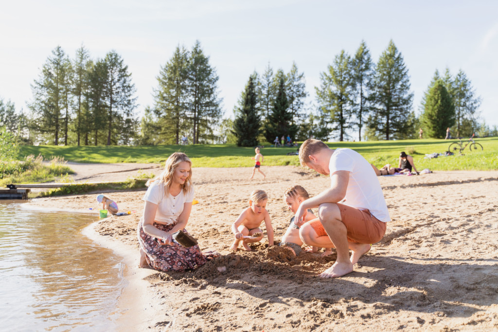 Perhe leikkimässä hiekalla Tanelinlammen uimarannalla