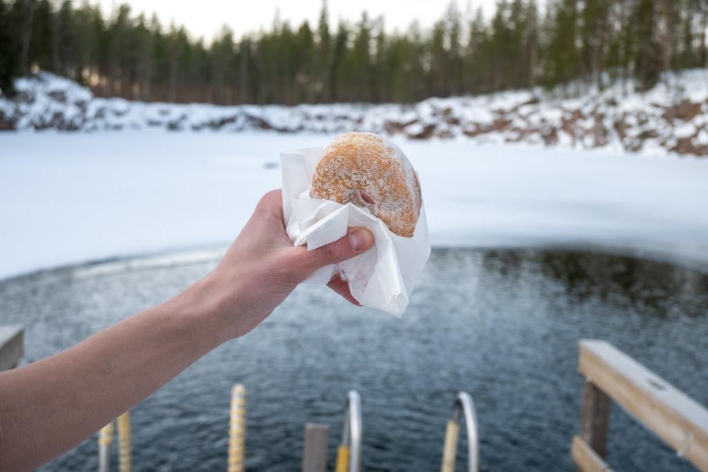 a Hand holding an pastry besides frozen lake in Seinäjoki